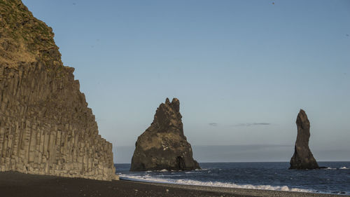 Rock formations in sea against clear blue sky