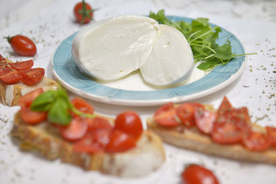 Sliced mozzarella on a plate with tomato bruschetta