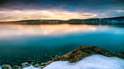 Beautiful sunrise on lake constance with stones on the lake shore and snow