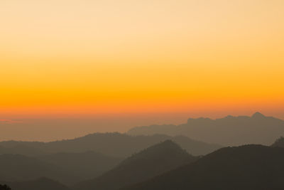 Scenic view of silhouette mountains against orange sky