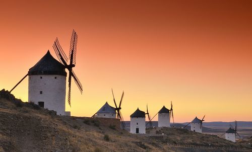 Traditional windmill on beach against sky during sunset