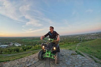 Portrait of man riding motorcycle on landscape against sky