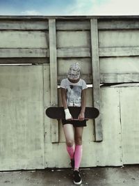 Full length of young woman standing against wall