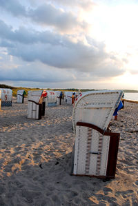 Hooded chairs on beach against sky