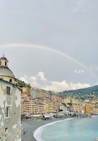 Rainbow over buildings in city against sky