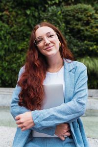 Businesswoman holding a laptop and looking at camera