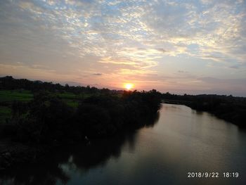 Scenic view of river against sky at sunset