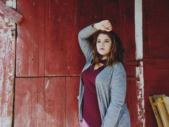 Portrait of young woman standing against brick wall