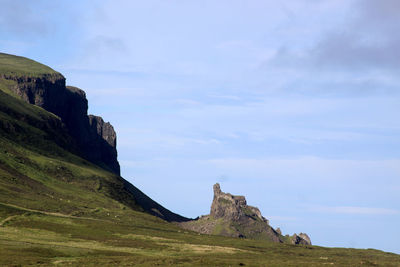 Rock formations on landscape against cloudy sky