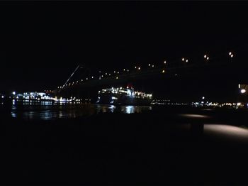 Illuminated bridge over river at night