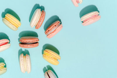 French dessert concept, colorful macarons in pastel tone on light blue background.