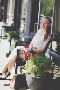 Young woman sitting on table by window