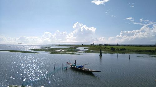 Boats in sea against cloudy sky