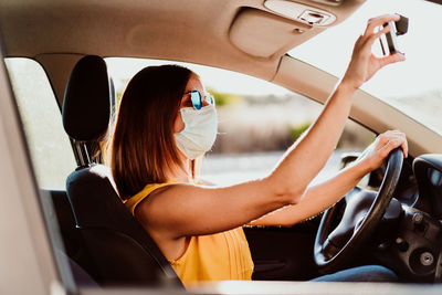 Portrait of young woman using phone while sitting in car