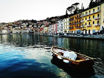 Boat moored in river against buildings in city