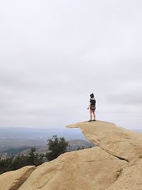 Woman standing on rock against sky