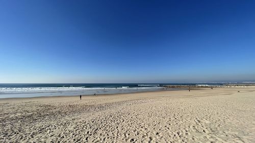 Scenic view of beach against clear blue sky