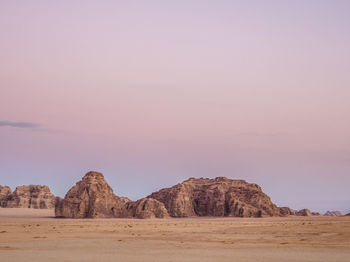 Rock formations in desert against sky during sunset