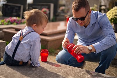 Father and son lighting a candle at the grave