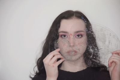 Portrait of a beautiful young woman with hand against white background