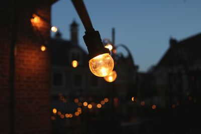 Low angle view of illuminated light bulb against sky at night