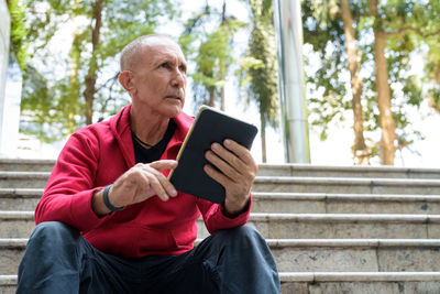 Man holding mobile phone while sitting outdoors