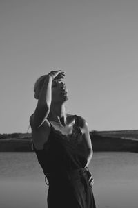 Woman standing on beach against clear sky