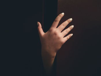 Close-up of woman hand on wall in darkroom