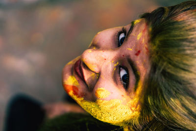 Close-up portrait of young woman with powder paint on face during holi