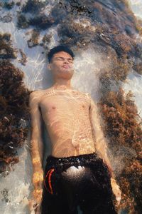 Portrait of shirtless man swimming in beach