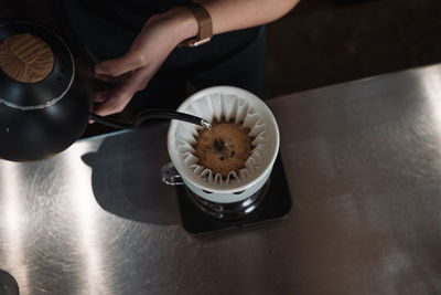 High angle view of hand holding coffee cup on table