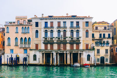 Buildings by canal against clear sky