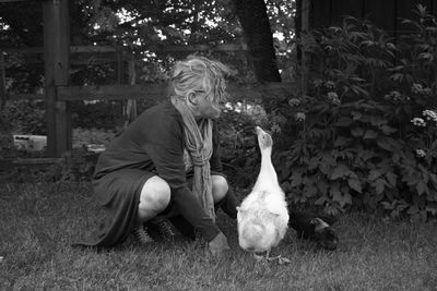 Woman with ducks on grassy field