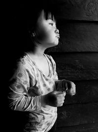 Girl looking away while standing against black background
