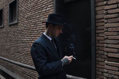 Man smoking cigarette against brick wall