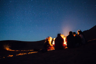 People enjoying campfire in desert at night