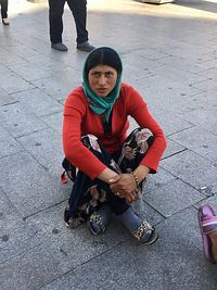 Portrait of young man sitting on footpath