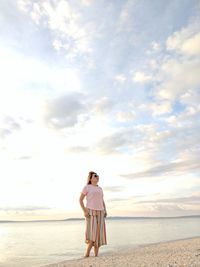 Woman standing on beach against sky