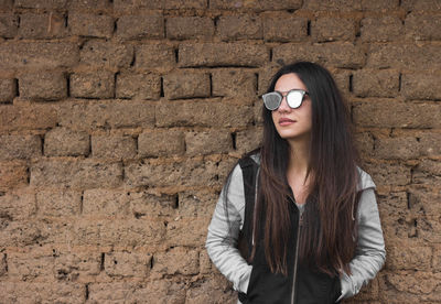 Portrait of woman standing against brick wall