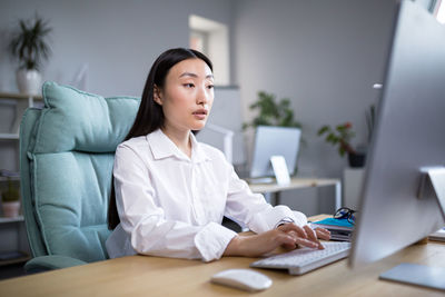 Portrait of young businesswoman using laptop at desk in office