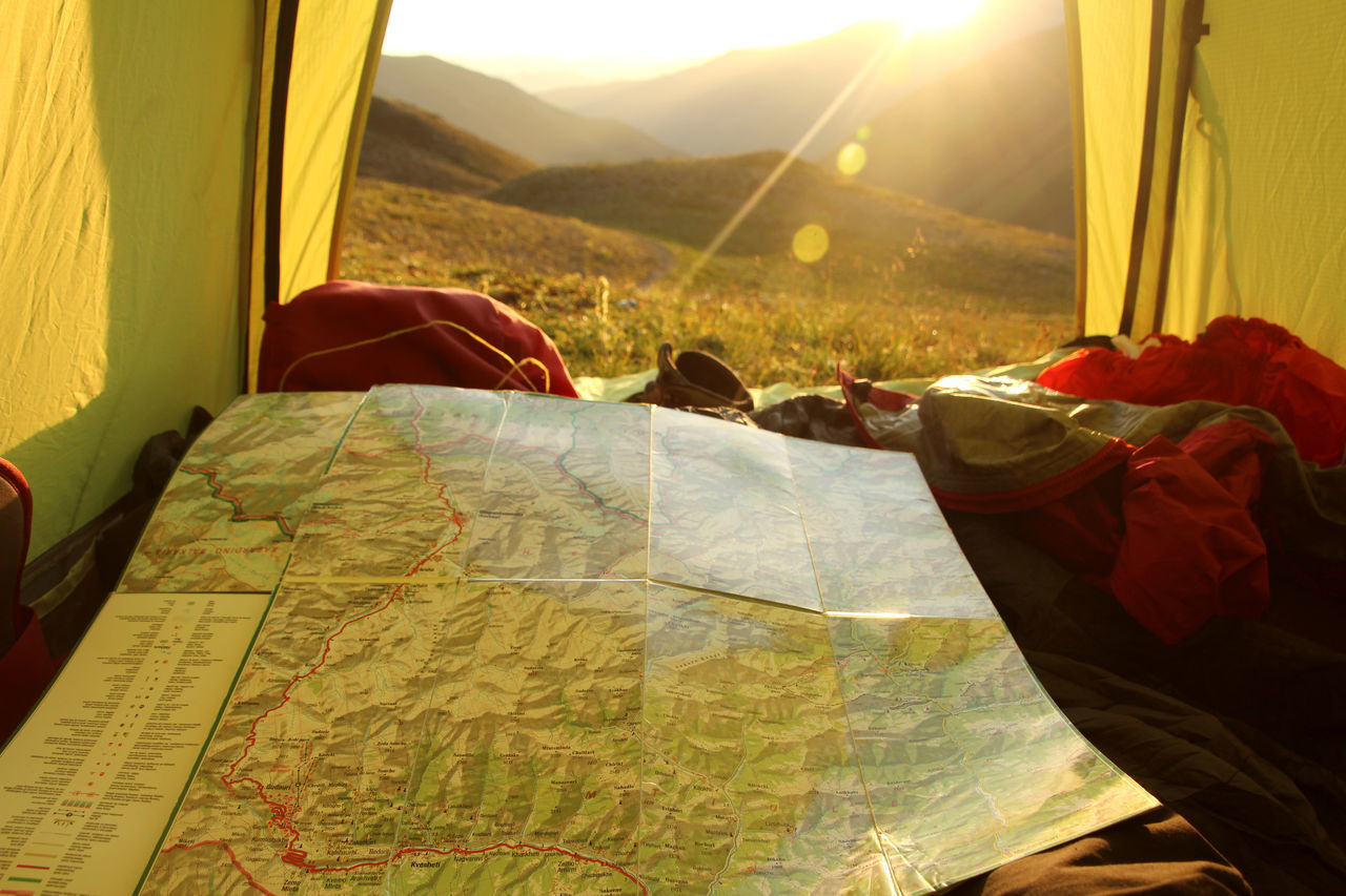 REAR VIEW OF PEOPLE IN TENT BY MOUNTAIN