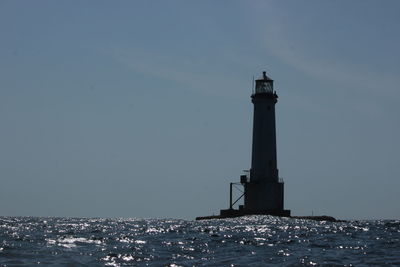 Lighthouse by sea against sky