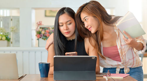 Young woman using phone while sitting on table