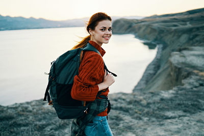 Side view of smiling young woman standing at shore