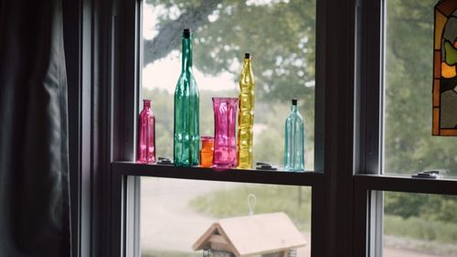 Close-up of bottles on window sill at home