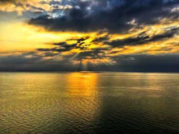 Scenic view of sea against dramatic sky during sunset