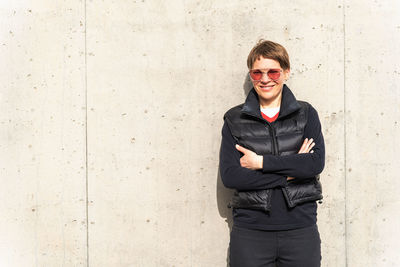 Portrait of young woman standing against wall
