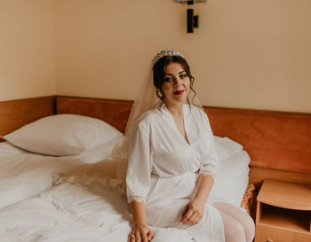 Young woman sitting on bed at home