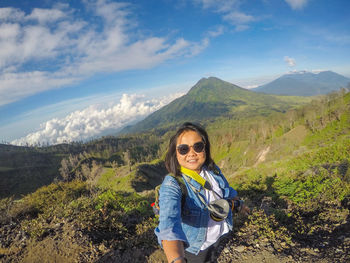 Woman wearing sunglasses standing on mountain against sky