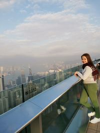 Woman standing on railing against cityscape